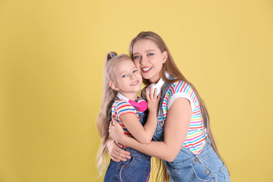 Photo of Happy mother and little daughter on yellow background