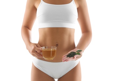 Photo of Young woman with fresh and dry leaves holding cup of diet tea on white background, closeup