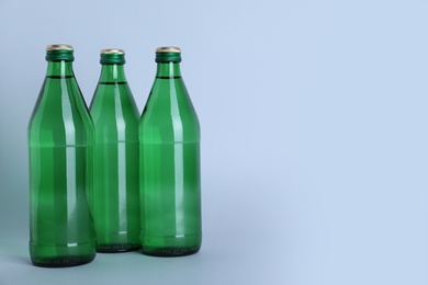 Glass bottles with water on white background, space for text