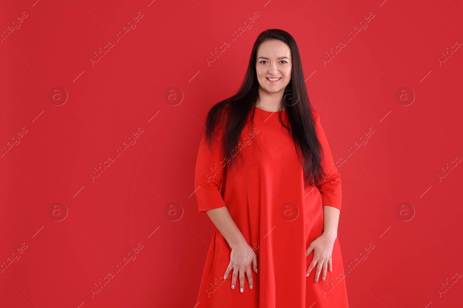 Photo of Beautiful overweight woman in dress on red background. Space for text