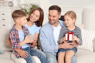 Happy family presenting each other with gifts on sofa at home