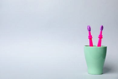 Photo of Baby toothbrushes in holder and space for text on color background