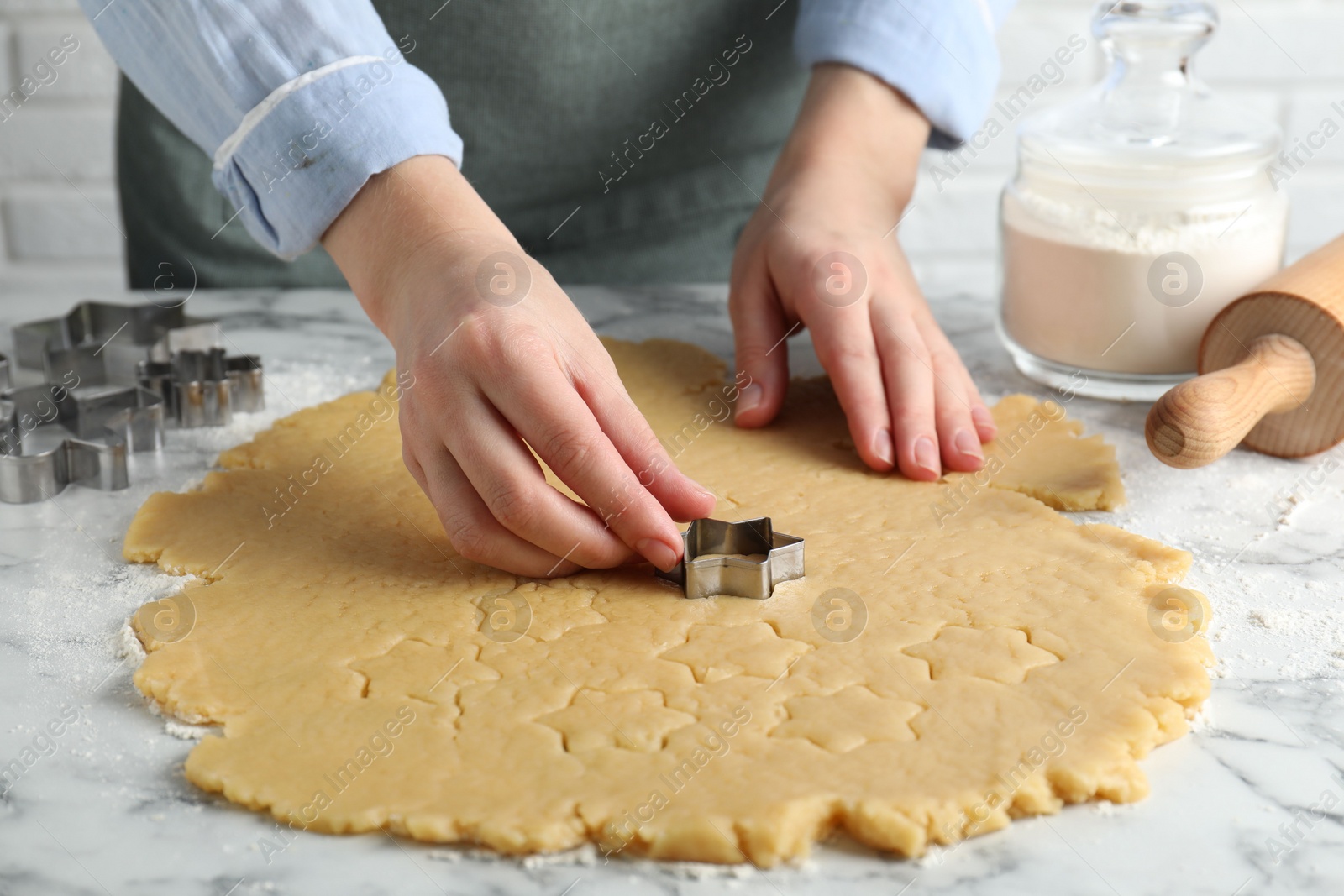 Photo of Shortcrust pastry. Woman making cookies with cutter at white marble table, closeup