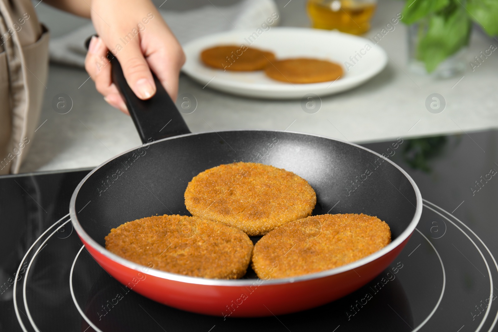 Photo of Woman cooking breaded cutlets in frying pan on stove, closeup