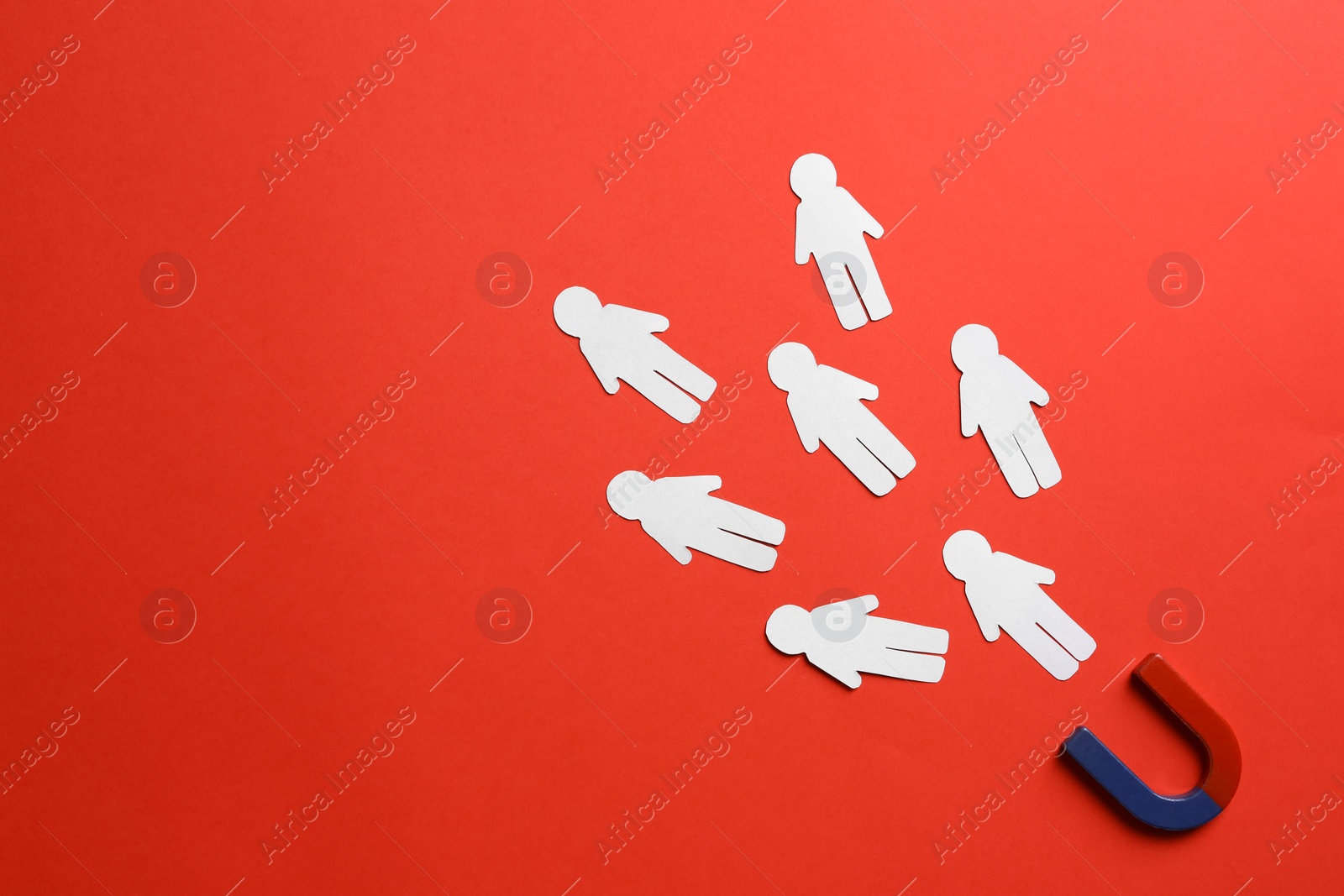 Photo of Magnet attracting paper people on red background, flat lay. Space for text