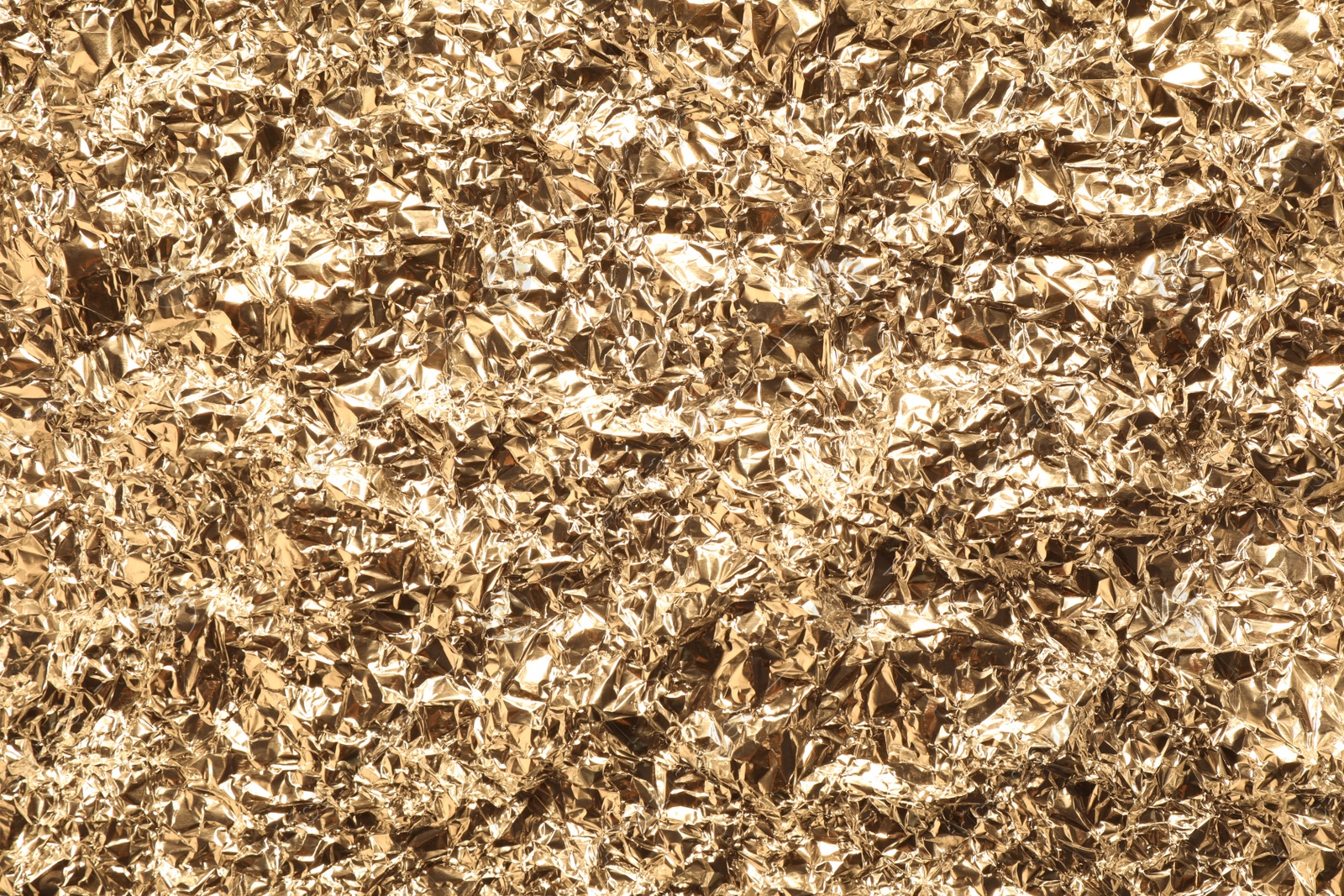 Photo of Crumpled gold foil as background, top view