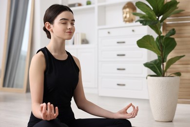 Beautiful girl meditating at home. Practicing yoga