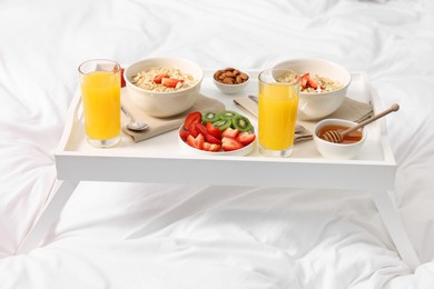 Photo of White tray with tasty breakfast on bed
