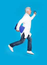 Photo of Senior doctor with clipboard and stethoscope running on light blue background