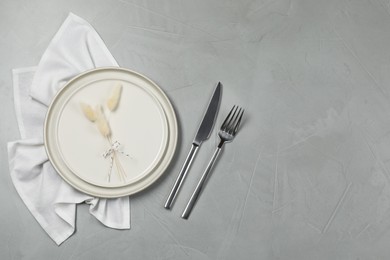 Photo of Stylish setting with elegant cutlery on grey table, top view. Space for text