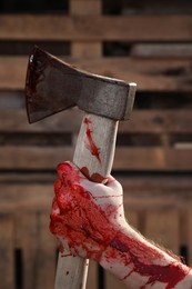 Photo of Man holding bloody axe outdoors, closeup view