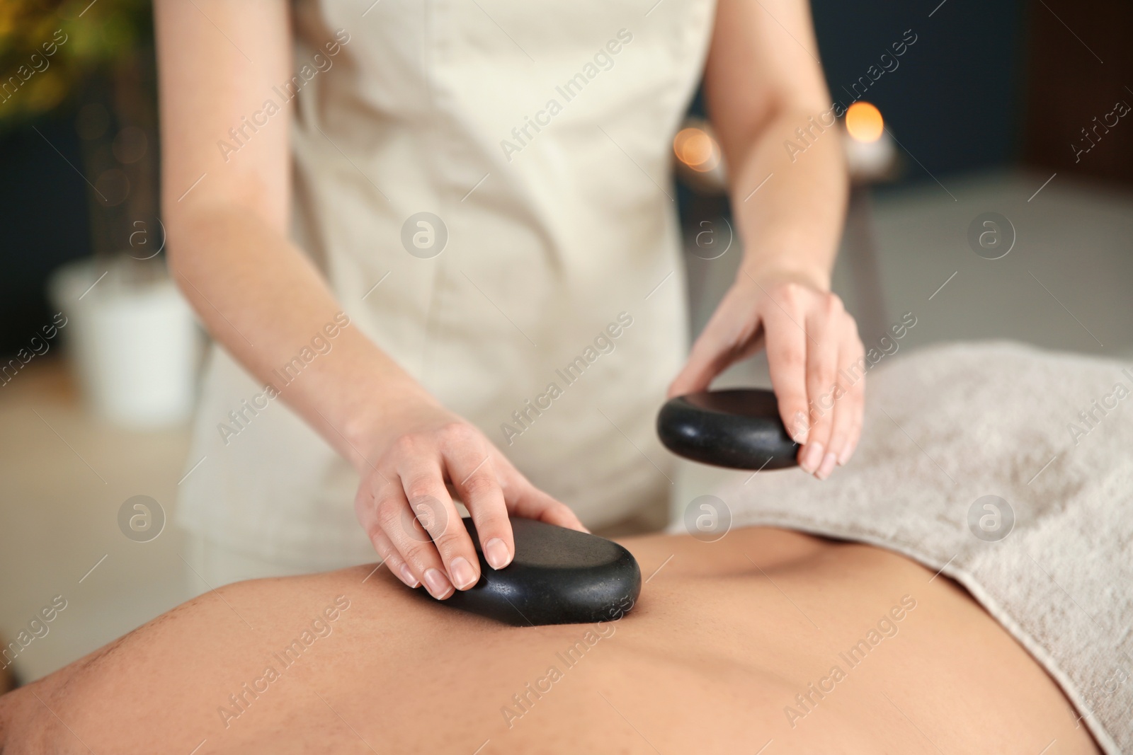 Photo of Man man receiving hot stone massage in spa salon, closeup