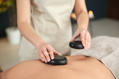 Man man receiving hot stone massage in spa salon, closeup