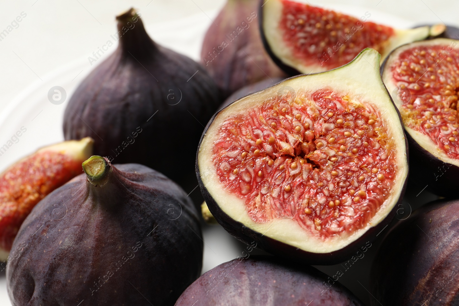 Photo of Whole and cut ripe figs on table, closeup
