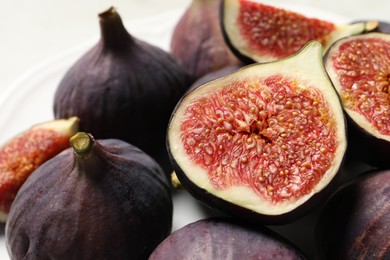 Photo of Whole and cut ripe figs on table, closeup