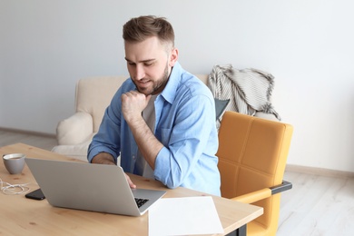 Photo of Young man working with laptop at desk. Home office