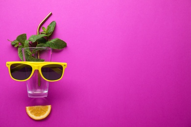 Photo of Creative image of summer cocktail made with mint, glass, sunglasses, citrus slice and straw on color background, flat lay. Space for text