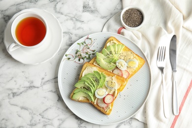 Plate of tasty toasts with avocado, quail eggs and chia seeds served on marble table, top view