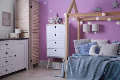 Photo of Child's room interior with comfortable bed and garland