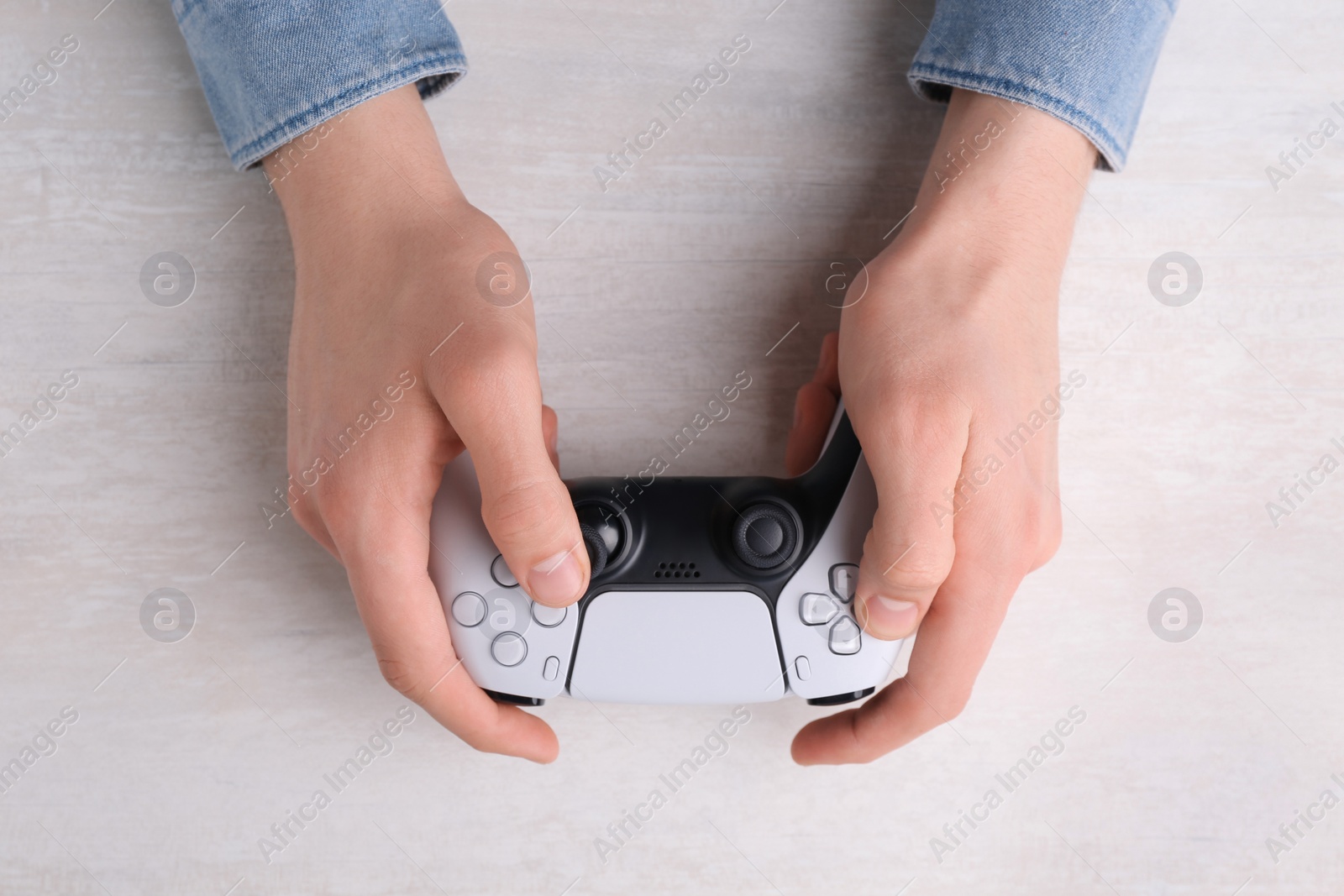 Photo of Man using wireless game controller at white table, top view