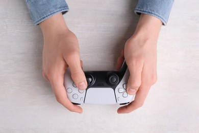 Photo of Man using wireless game controller at white table, top view