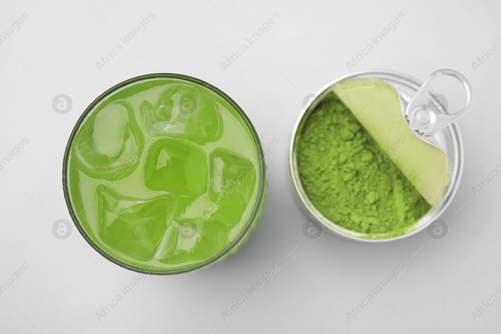 Photo of Glass of delicious iced green matcha tea and powder on white background, flat lay