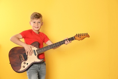 Photo of Little boy playing guitar on color background. Space for text