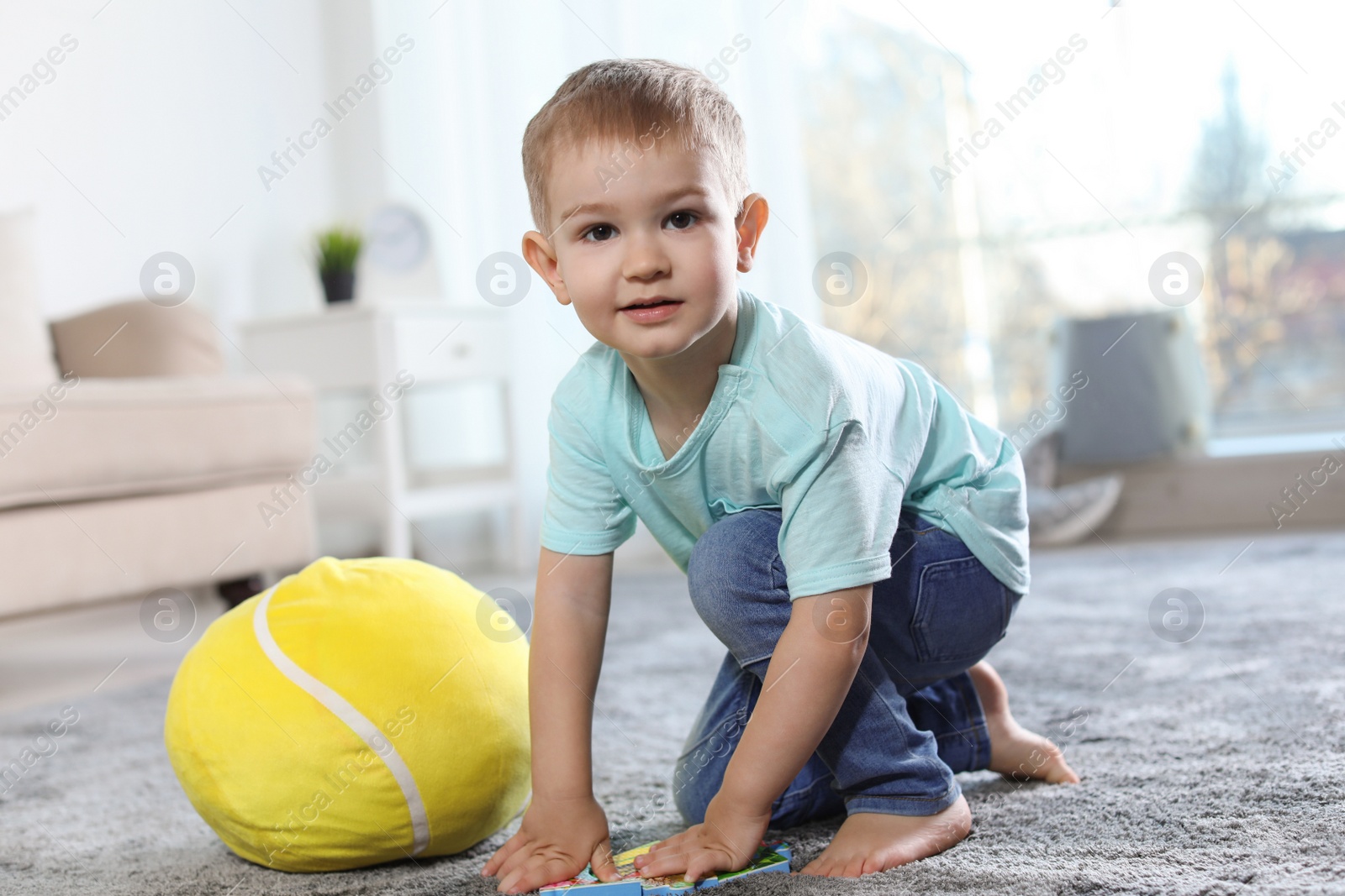 Photo of Cute child playing with soft toy on floor indoors