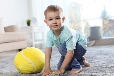 Cute child playing with soft toy on floor indoors
