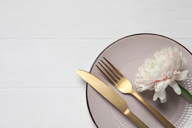 Stylish table setting with cutlery and flower on white wooden background, top view. Space for text