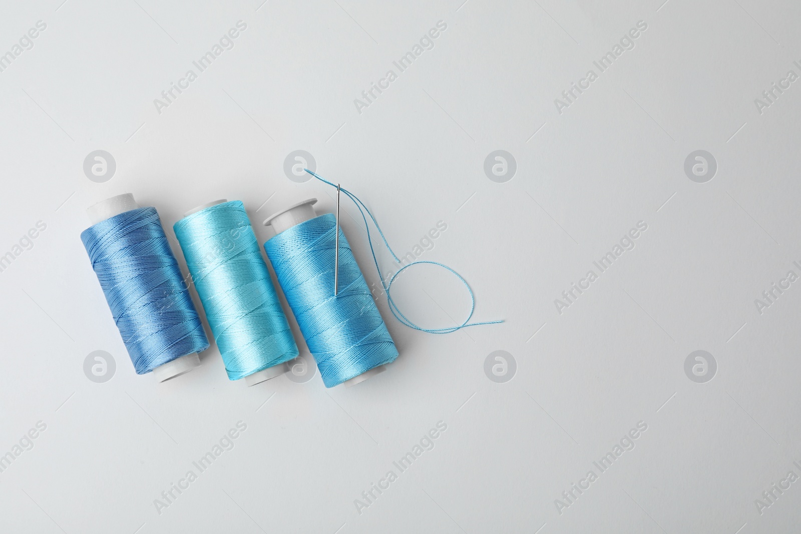 Photo of Color sewing threads on white background, top view