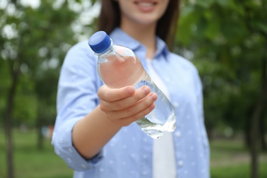 Photo of Woman holding bottle with water outdoors, closeup