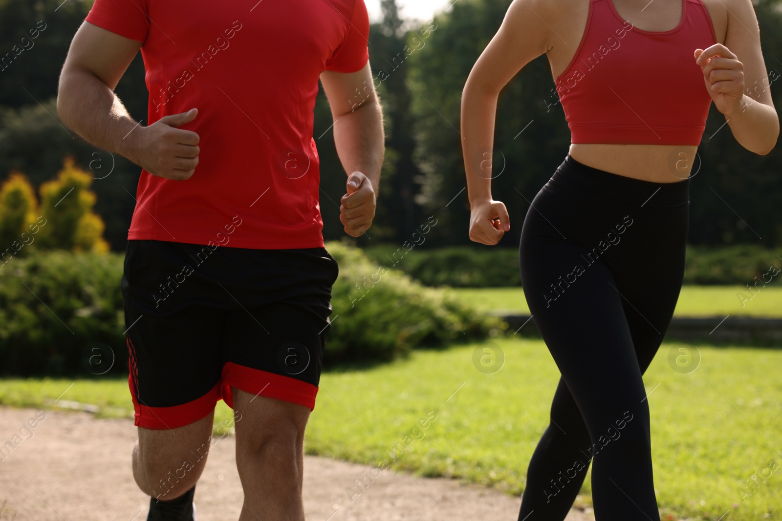 Photo of Healthy lifestyle. Couple running outdoors on sunny day, closeup