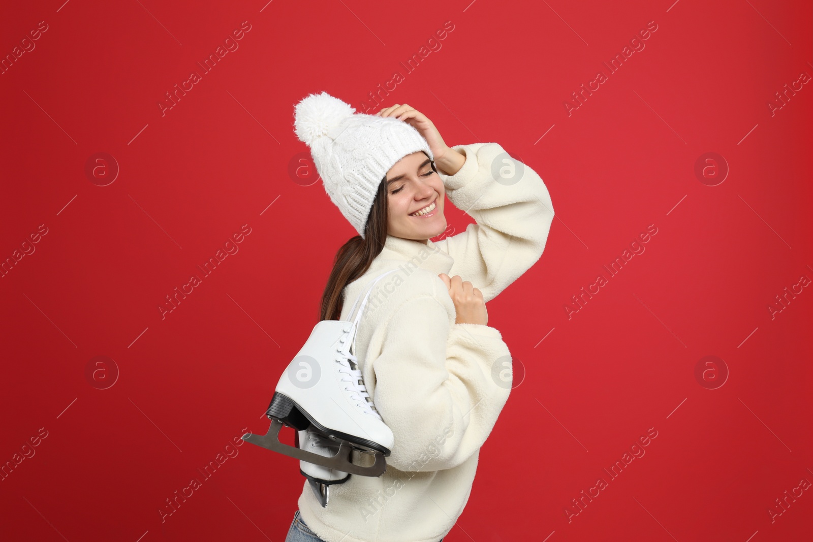 Photo of Happy woman with ice skates on red background