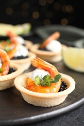 Delicious canapes with shrimps and black caviar on table, closeup