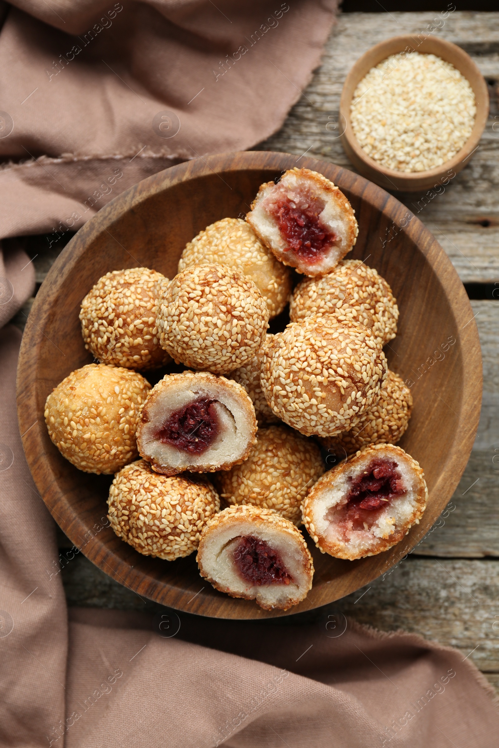 Photo of Delicious sesame balls with red bean paste on wooden table, flat lay