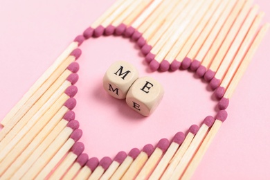 Photo of Love Me. Creative composition with matches and cubes on pink background