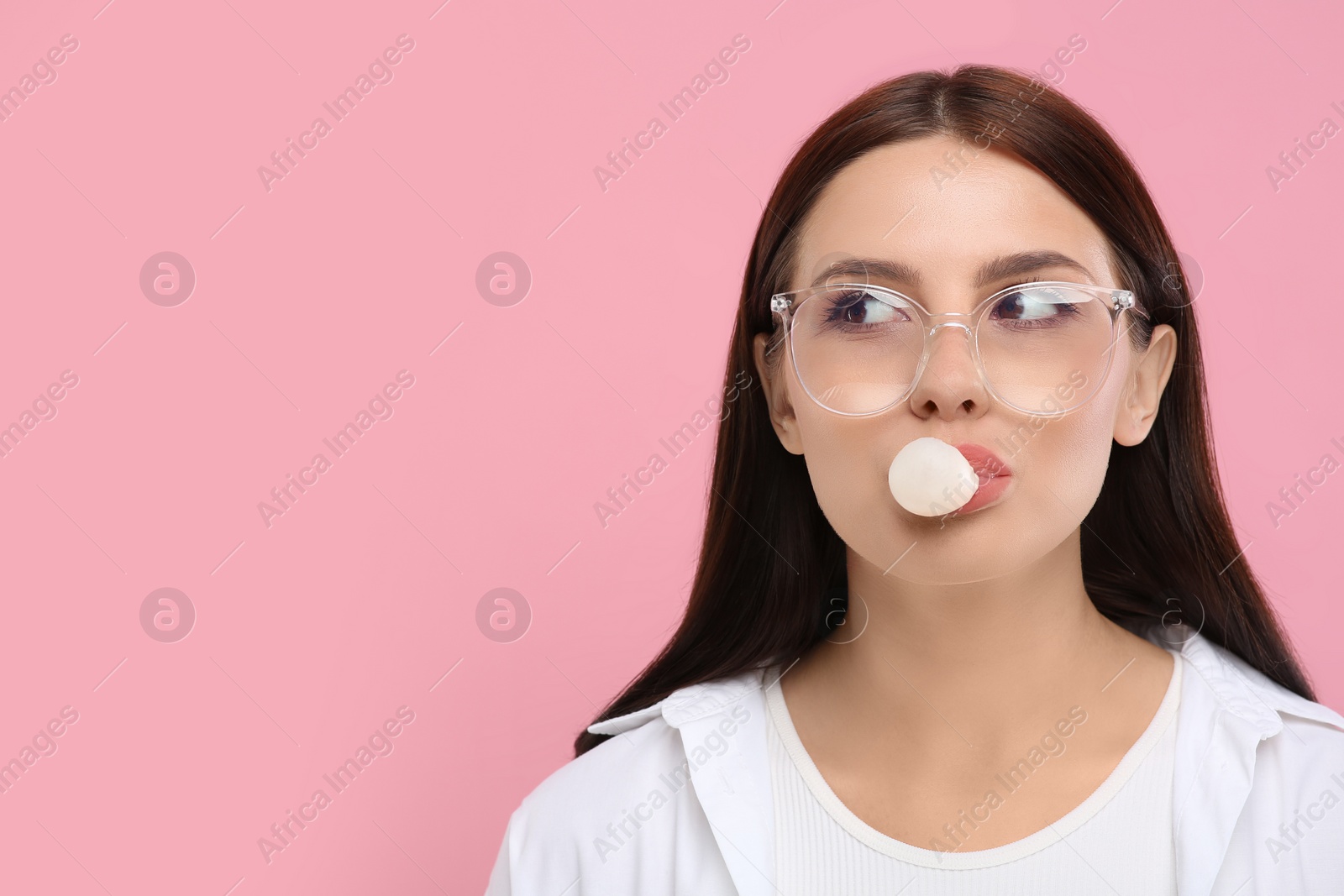 Photo of Beautiful woman blowing bubble gum on pink background, space for text