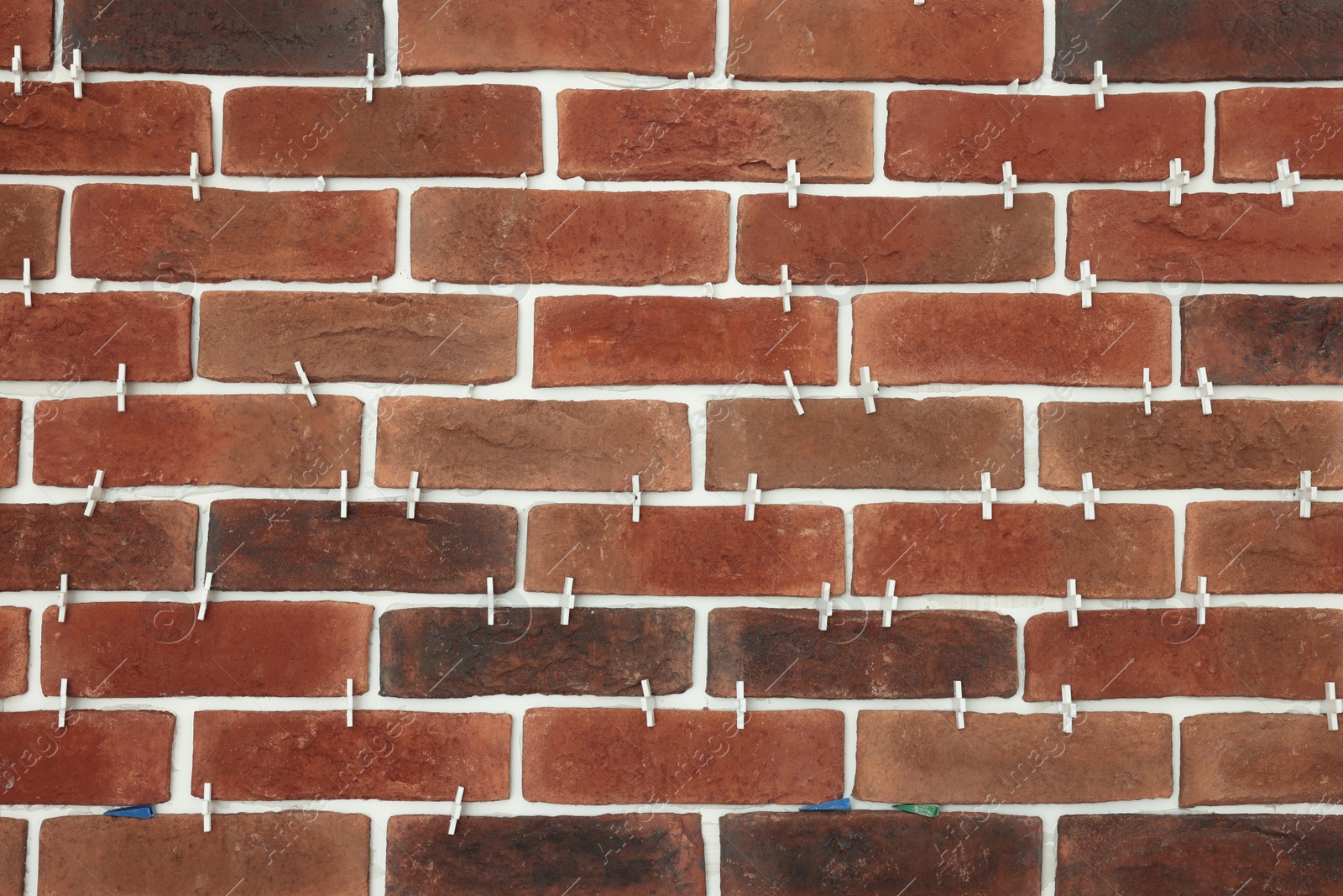 Photo of Decorative bricks with tile leveling system on wall