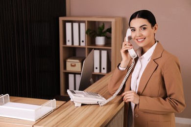 Photo of Receptionist talking on phone near countertop in office, space for text
