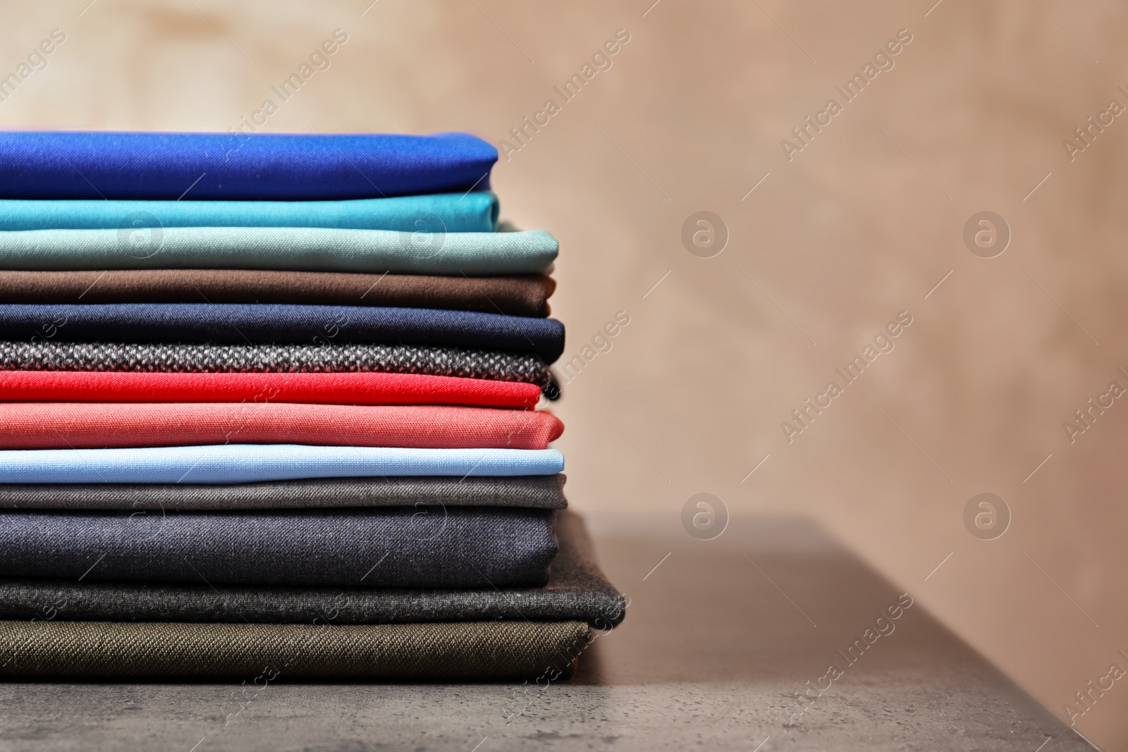 Photo of Stack of colorful fabrics for tailoring on table