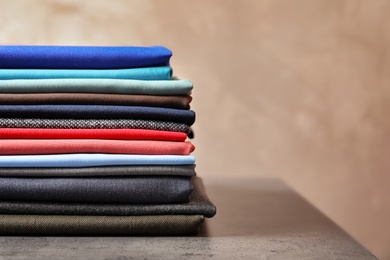 Photo of Stack of colorful fabrics for tailoring on table