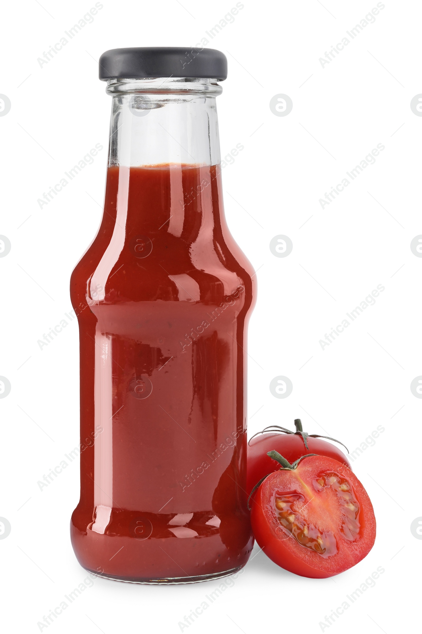 Photo of Glass bottle of tasty ketchup and fresh tomatoes isolated on white