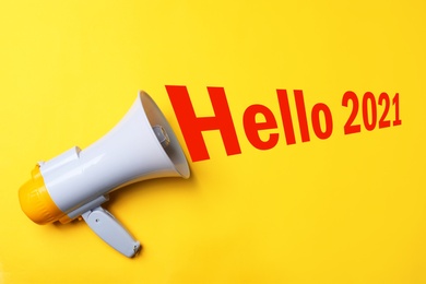 Image of Hello 2021. Megaphone on yellow background, top view