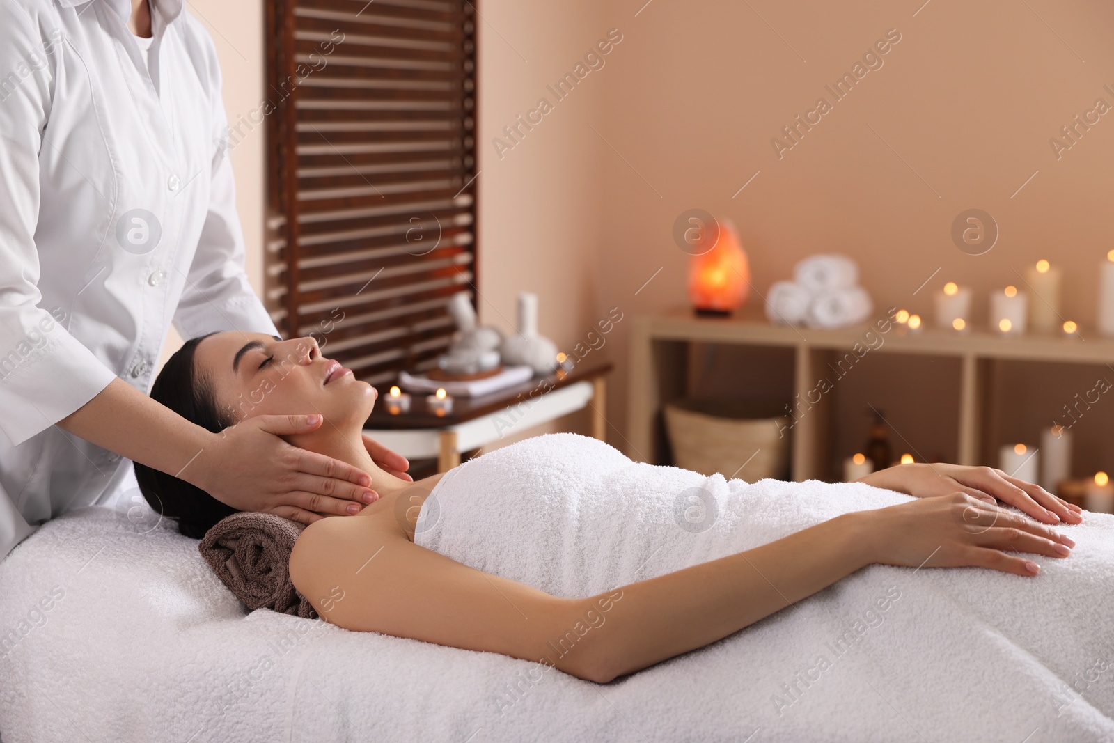 Photo of Young woman enjoying professional massage in spa salon
