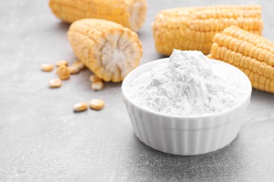 Photo of Bowl with corn starch and ripe cobs on light grey table, closeup. Space for text