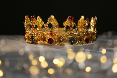 Photo of Beautiful golden crown and fairy lights on black background. Fantasy item