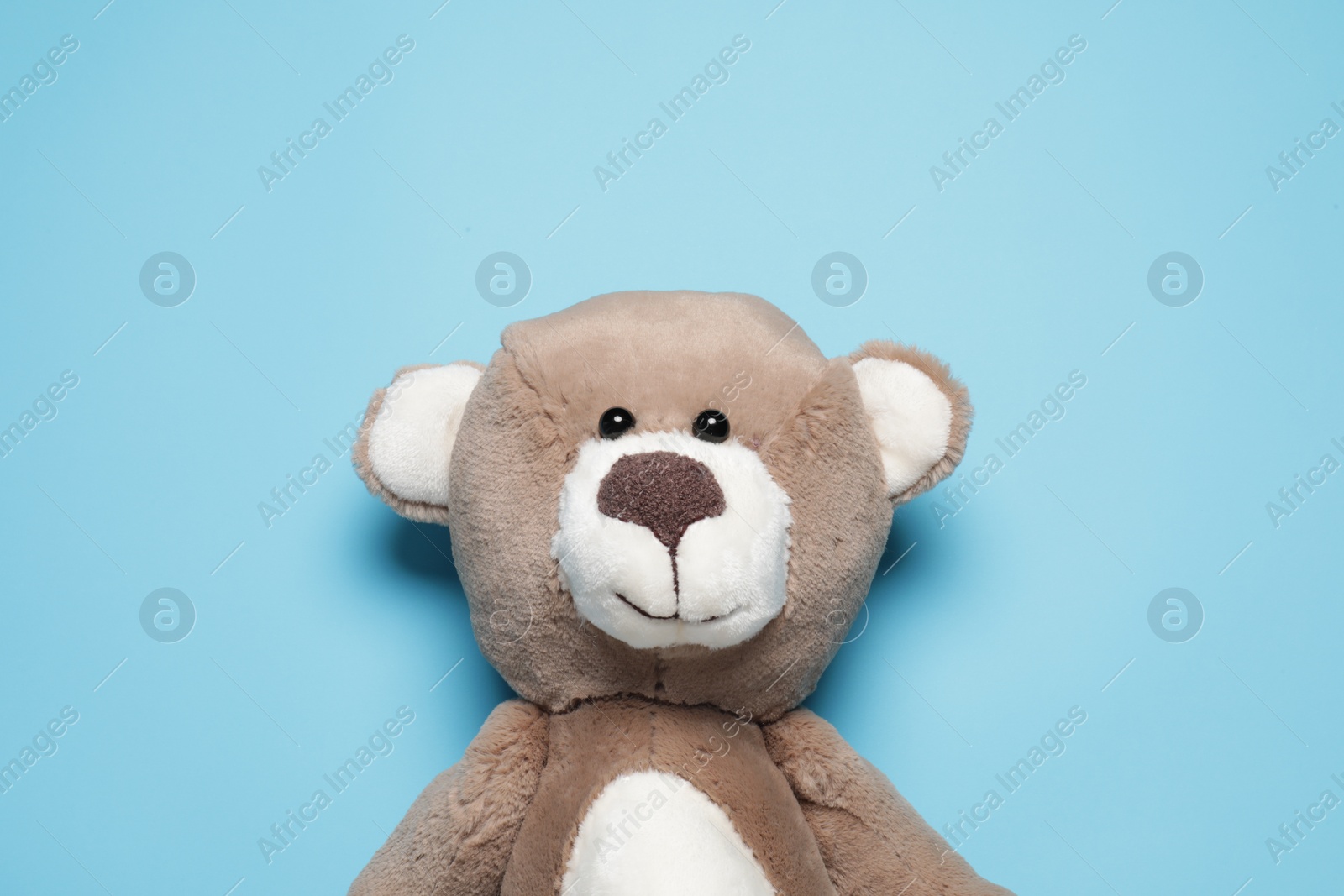 Photo of Cute teddy bear on light blue background, top view. Space for text