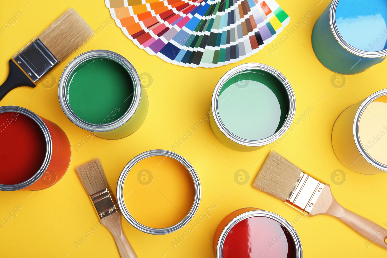 Photo of Flat lay composition with paint cans, brushes and color palette on yellow background