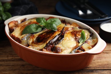 Photo of Delicious eggplant lasagna in baking dish on wooden table, closeup